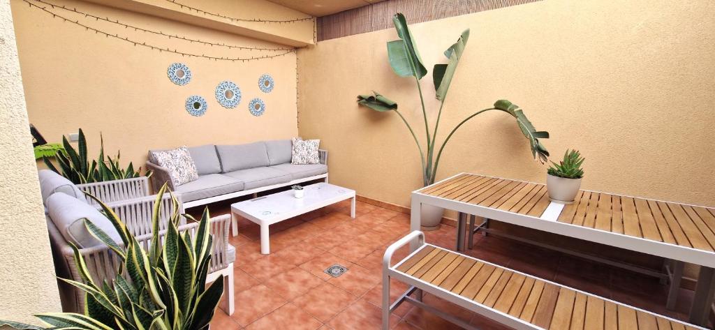Casa Cotillo 13 next to Los Lagos Beach Highspeed Wifi في كوتيو: غرفة معيشة مع أريكة وطاولات ونباتات