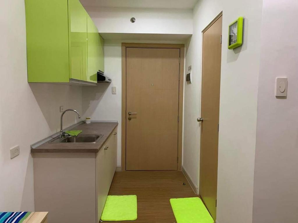 - une cuisine avec des placards verts, un évier et une porte dans l'établissement Grace Residences Taguig City, à Manille