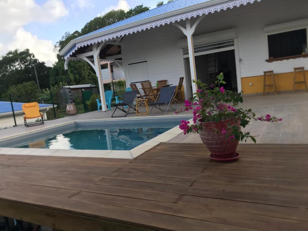 a house with a pool and a deck with flowers at Bungalow Candy avec piscine in Rivière-Salée