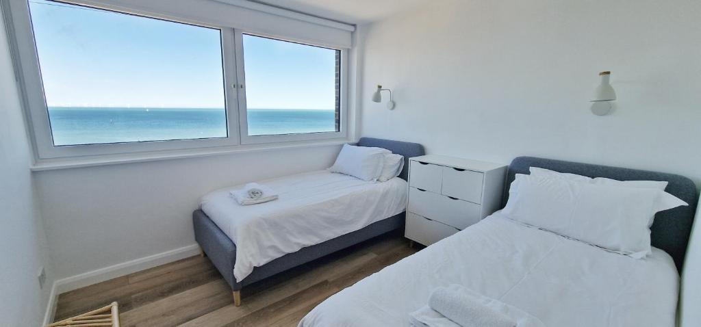 a bedroom with two beds and a window with the ocean at The Beach House in Kent