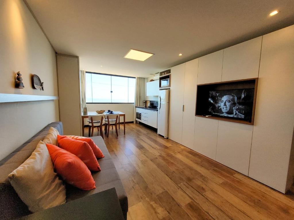 uma sala de estar com um sofá e uma cozinha em Loft 320 - Residence Farol em Laguna