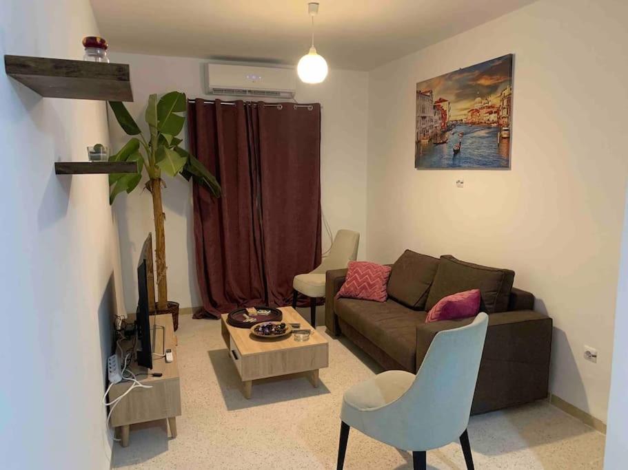 uma sala de estar com um sofá e uma mesa em Appartement 5 lits climatisé salon 2chambres cuisine équipée SDB em Staoueli