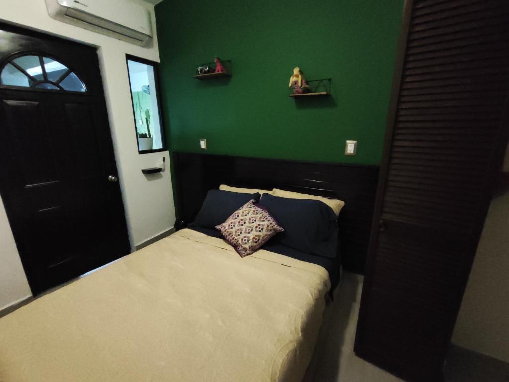 een kleine slaapkamer met een bed en een groene muur bij Las viejitas, la casita más bonita del centro de Tuxtla Gutiérrez in Tuxtla Gutiérrez