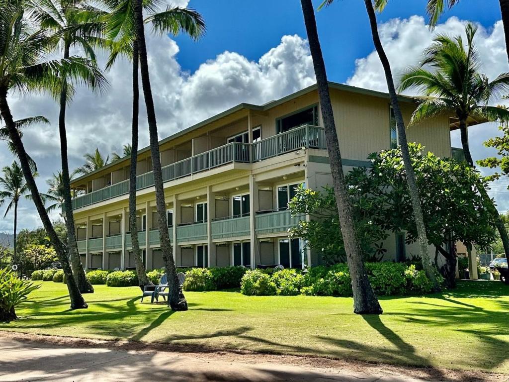 a large building with palm trees in front of it at Hotel Coral Reef in Kapaa