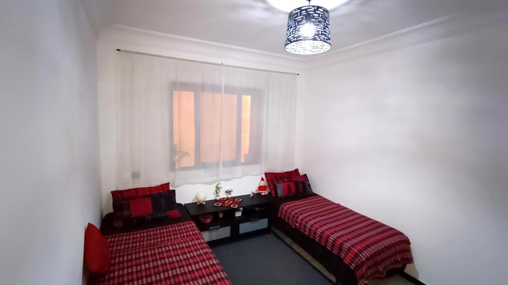 Zimmer mit 2 Betten, einem Fenster und einem Tisch in der Unterkunft Dar Shama - Women only in Rabat
