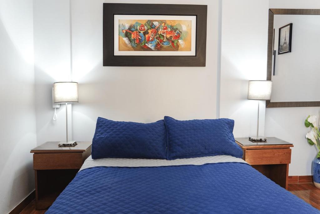 1 dormitorio con 1 cama azul y 2 lámparas en Montreal Hostal, en Lima