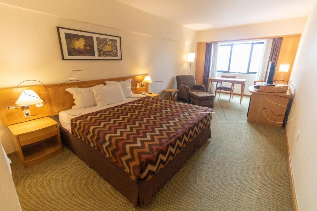 バルエリにあるHotel Alphavilleのベッドとテーブルが備わるホテルルームです。