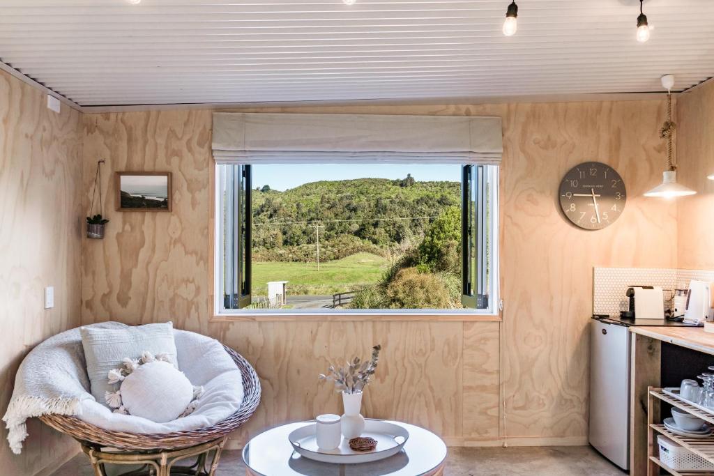 a small living room with a chair and a window at Flaxpod Cabin in Raglan