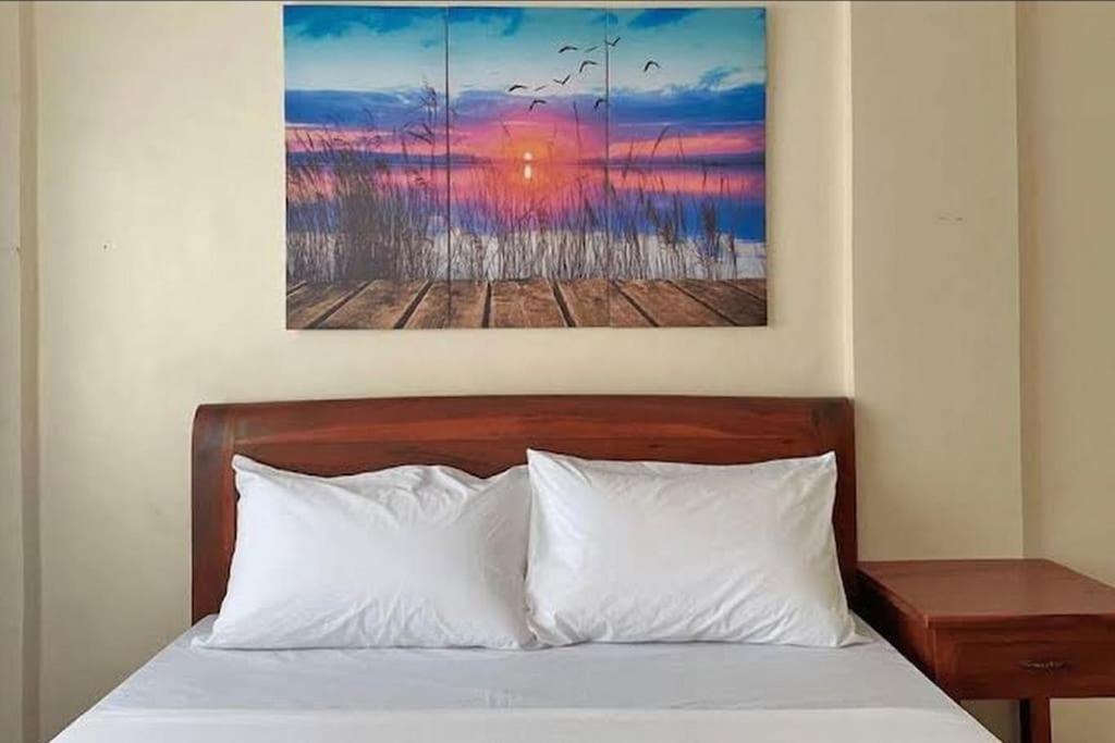 1 cama con almohadas blancas y una pintura en la pared en Lawton Residences Studio Room 3A, en Manila