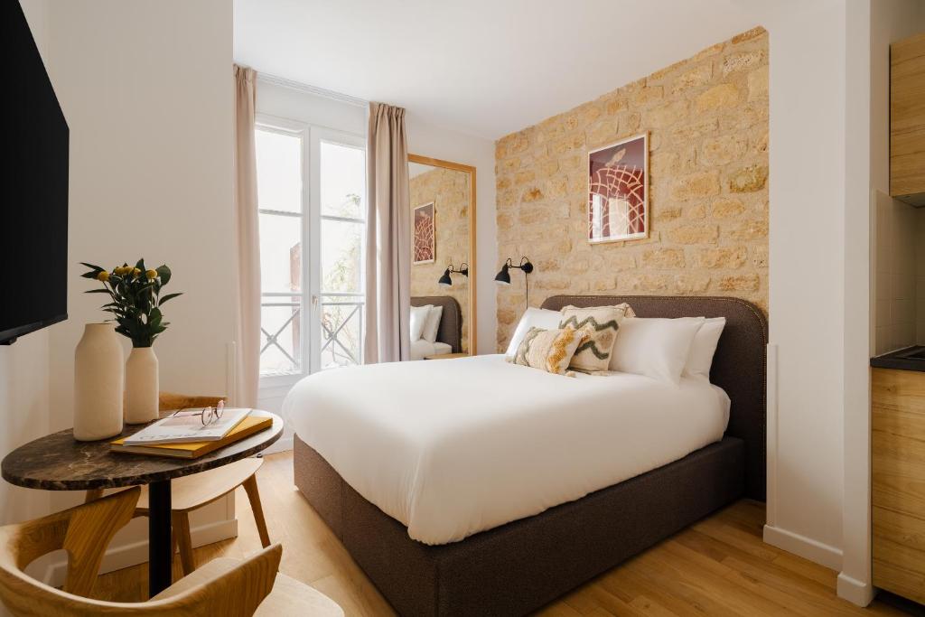 パリにあるオテル レジデンス カンティニ スクエアのベッドルーム(白いベッド1台、テーブル付)