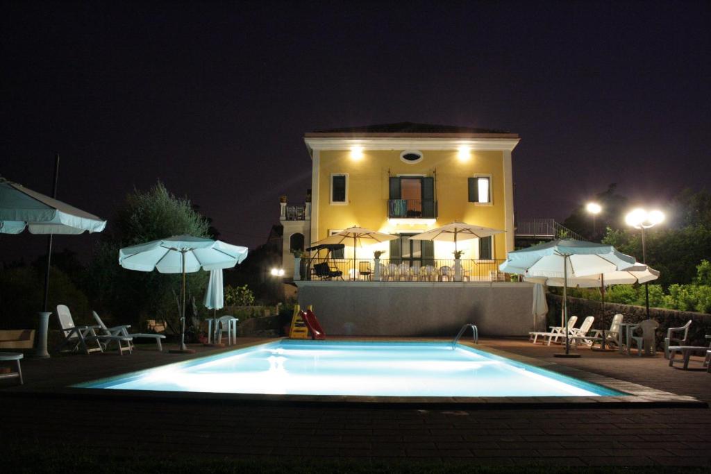 a swimming pool in front of a house at night at Villa Sciare Modò in Acireale