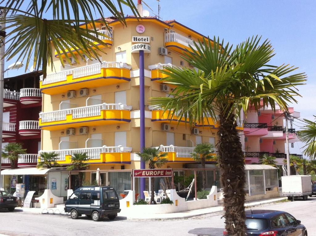 a building with a palm tree in front of it at Hotel Europe Inn in Paralia Katerinis
