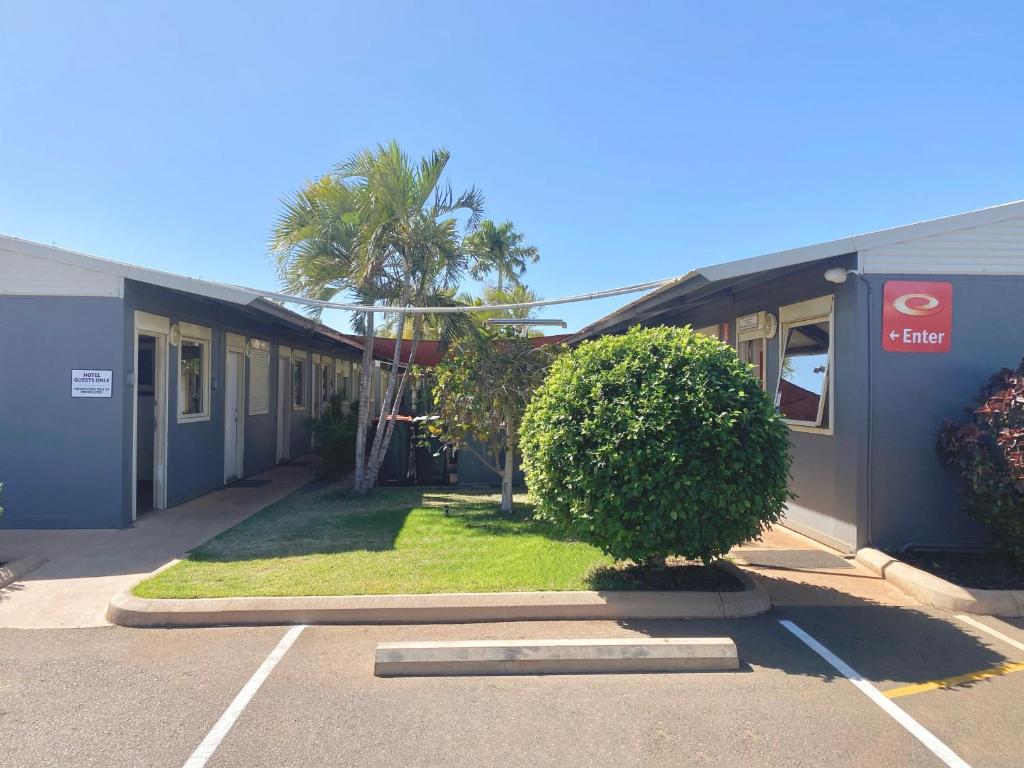 a building with a palm tree in a parking lot at Econo Lodge Karratha in Karratha