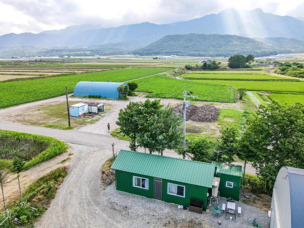 an aerial view of a farm with a house and a road at Furano Log House Farm Resort in Furano