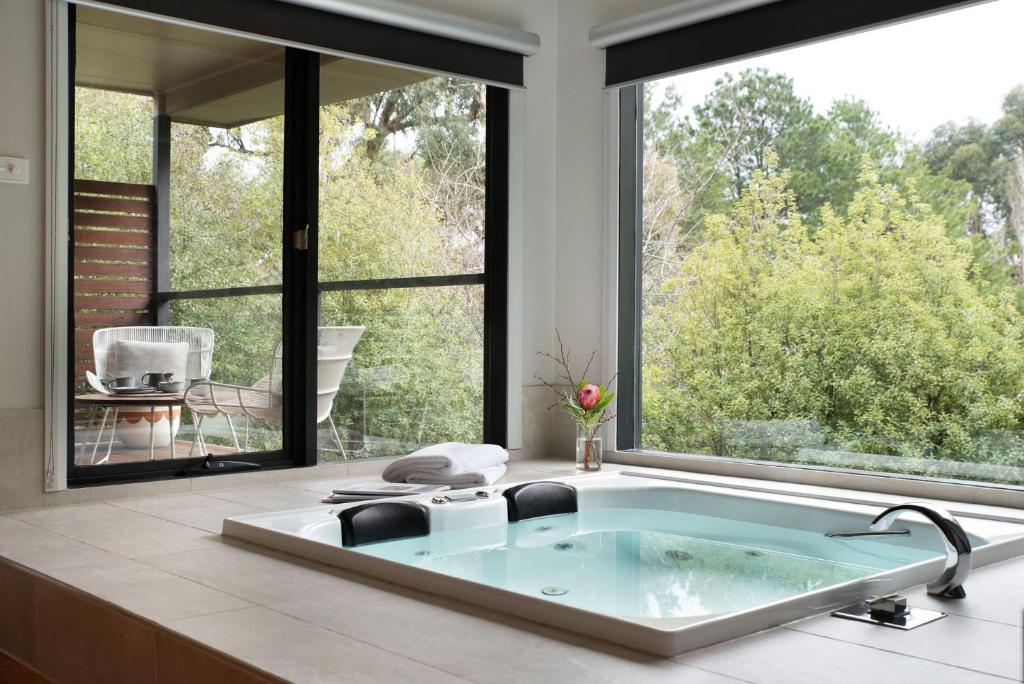 a bathroom with a bath tub with a large window at Schafhalle in Hepburn Springs