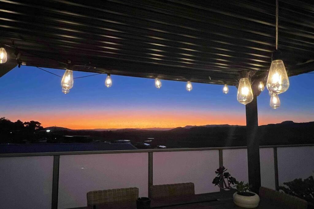 een patio met verlichting en uitzicht op de zonsondergang bij Mountain Views (3 min drive to beach) in Gerringong