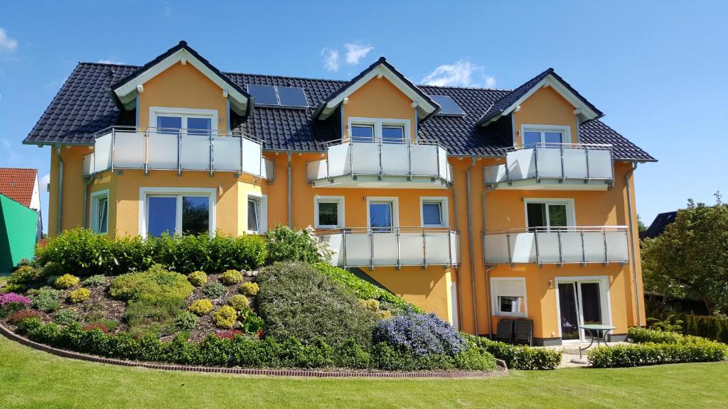 Una gran casa amarilla con un jardín enfrente. en Zuhause am Meer en Grömitz