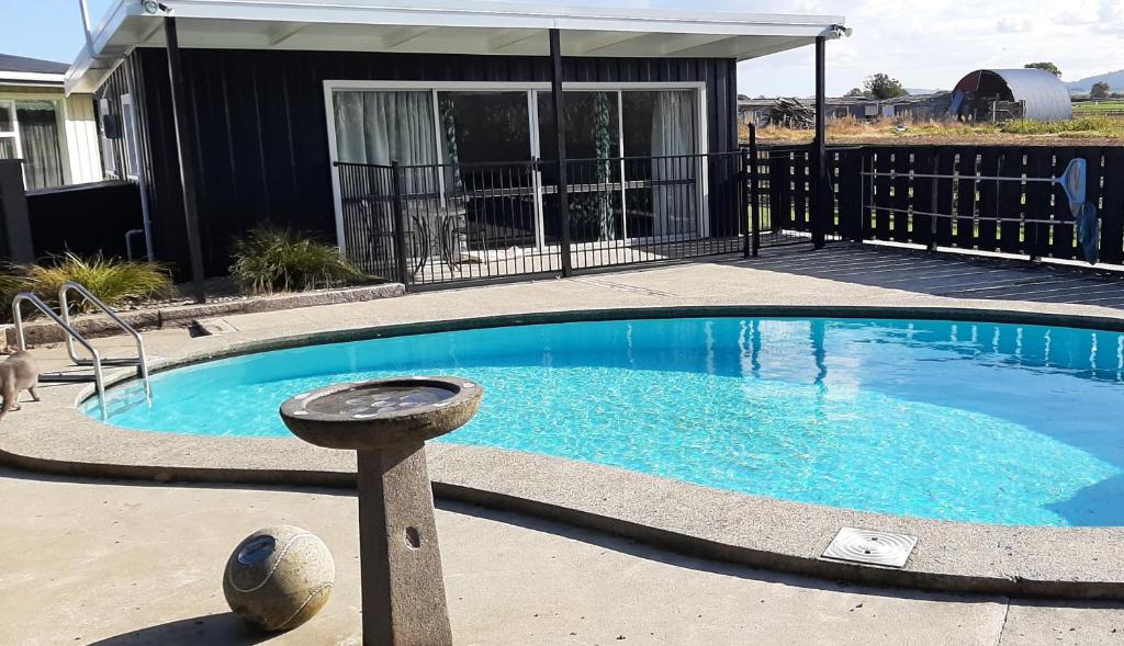a swimming pool in a yard with a house at The Poolhouse in Matamata