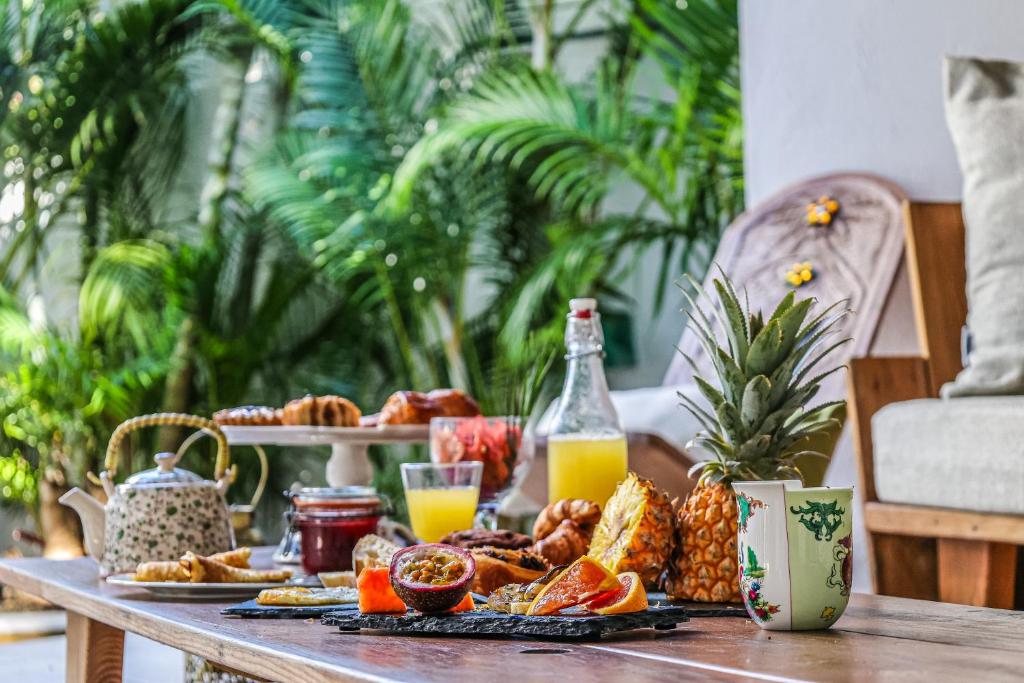 a table with a breakfast of food and orange juice at Guest House et Restaurant Sous le Badamier in Grand-Baie