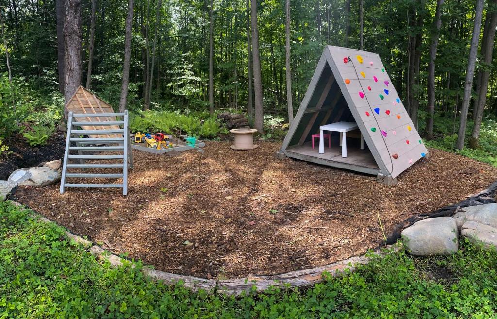 a play structure with a ladder in a backyard at Le Camp Caché Shefford in Shefford