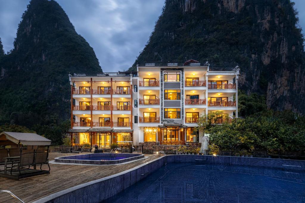 a hotel with a pool in front of a mountain at Yangshuo Shanshuiyao Resort - Free Train Station Pick Up and Drop Off in Yangshuo