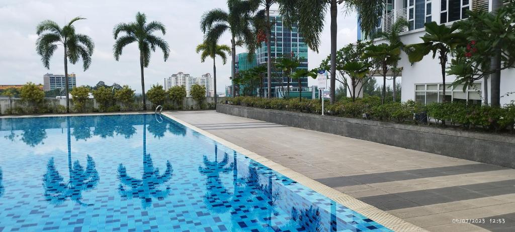 a swimming pool with palm trees and a building at SofiaSuite16, Plaza Azalea, Shah Alam in Shah Alam