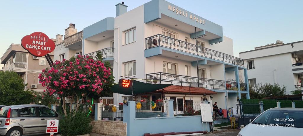 a large white building with a sign in front of it at NEŞELİ APART BAHÇE CAFE in Seferihisar