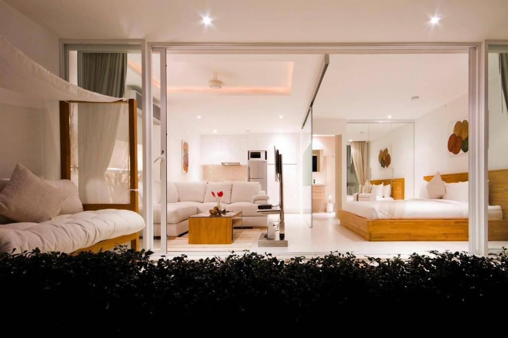 a living room with white furniture and a large mirror at Code Samui Hotel in Mae Nam