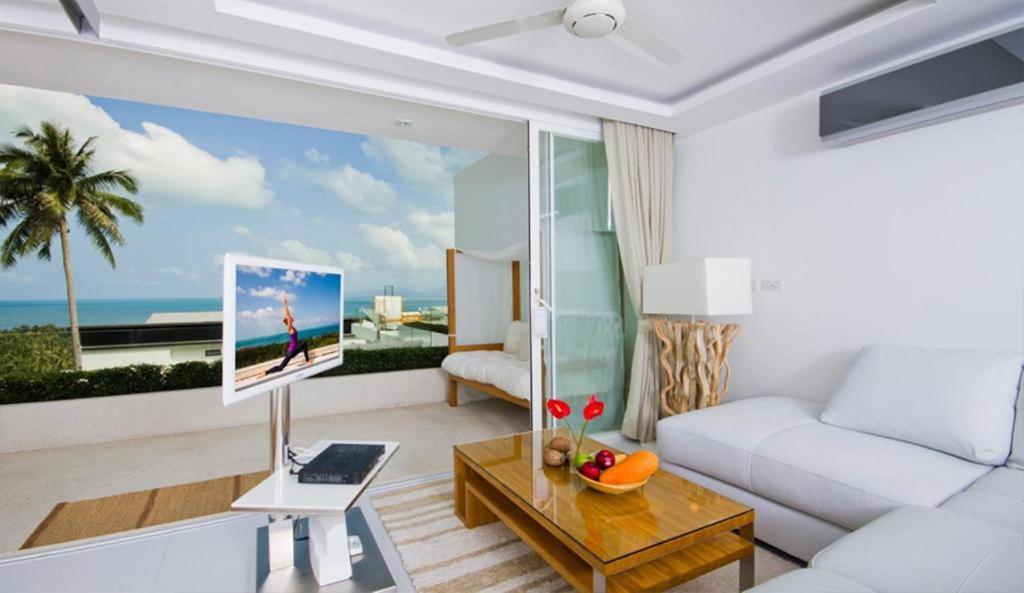 a living room with a white couch and a view of the ocean at Code Samui Hotel in Mae Nam