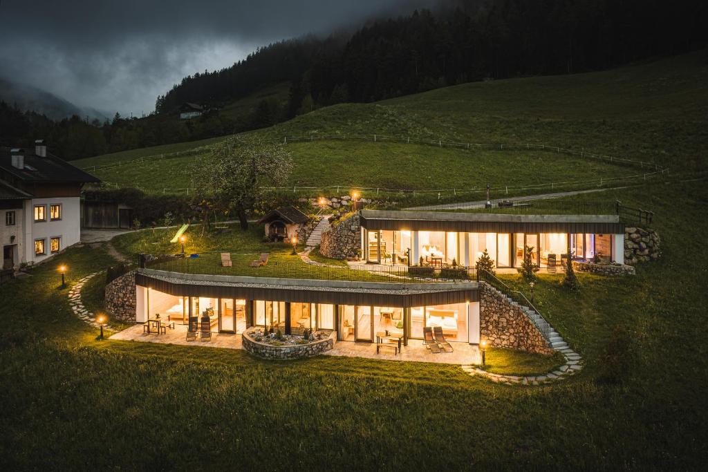 une grande maison sur une colline la nuit dans l'établissement Innermoser Bauernhof - Chalets, à Molini di Tures