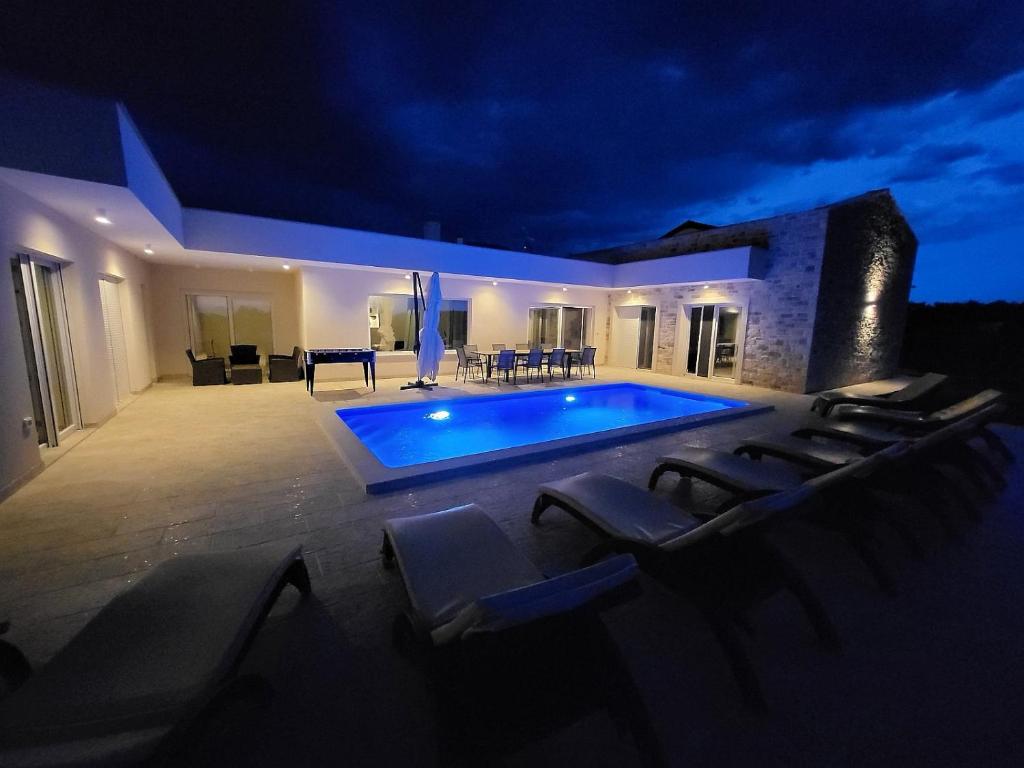 a swimming pool with lounge chairs around it at night at Villa Mare e Monti with heated pool in Umag