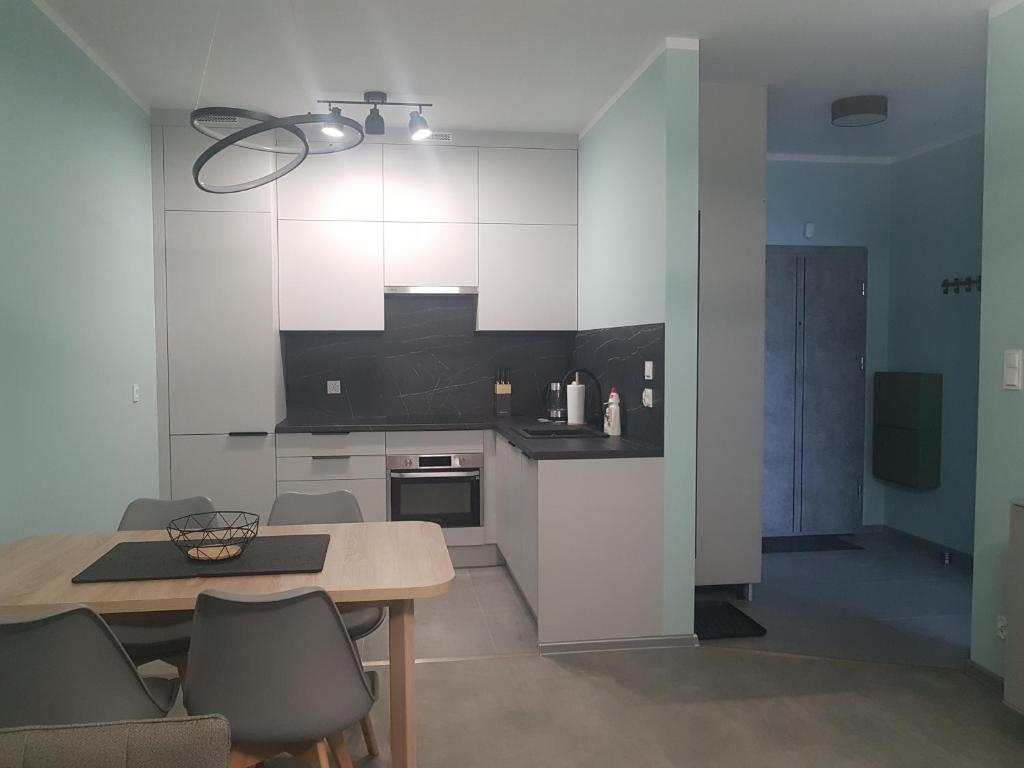 a kitchen with white cabinets and a table and chairs at Apartament ul. Marzeń in Kostrzyn nad Odrą