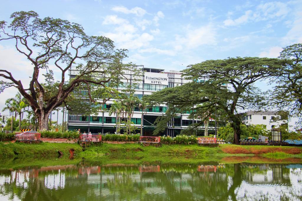 a building in front of a pond in front of a building at Flemington Hotel in Taiping
