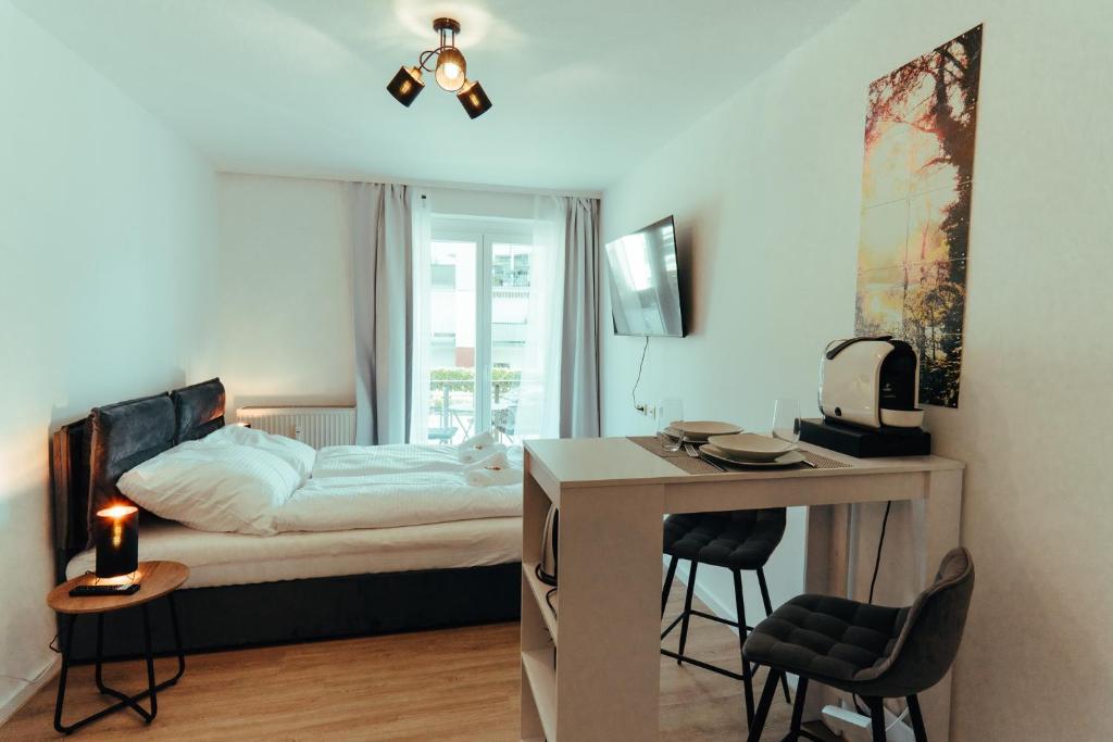 a bedroom with a bed and a desk and a table with chairs at Apartment modern und gemütlich ggü. Uni-Passau, TG-Stellplatz, Balkon in Passau