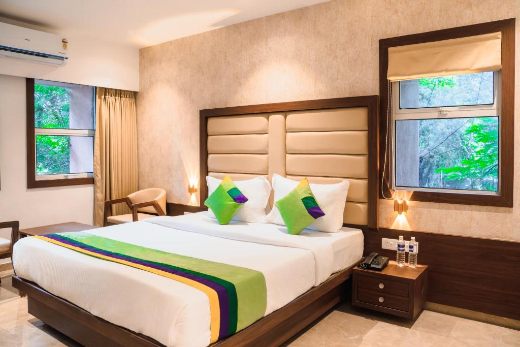 a bedroom with a large bed and two windows at Treebo Trend Serenity Inn in Pune