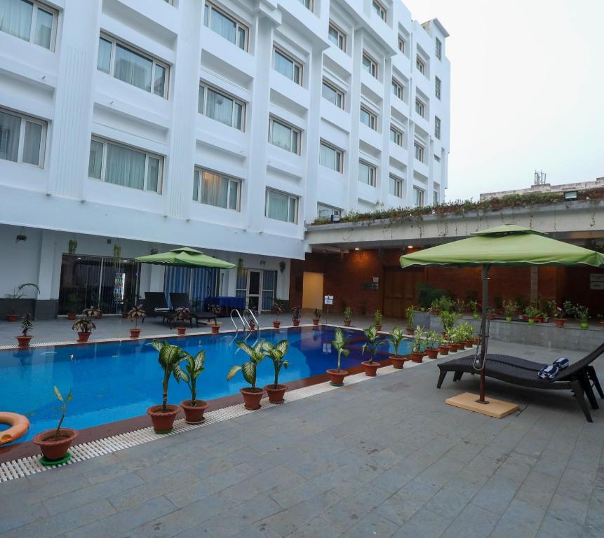 a hotel with a swimming pool with umbrellas and plants at IRA By Orchid Bhubaneswar in Bhubaneshwar