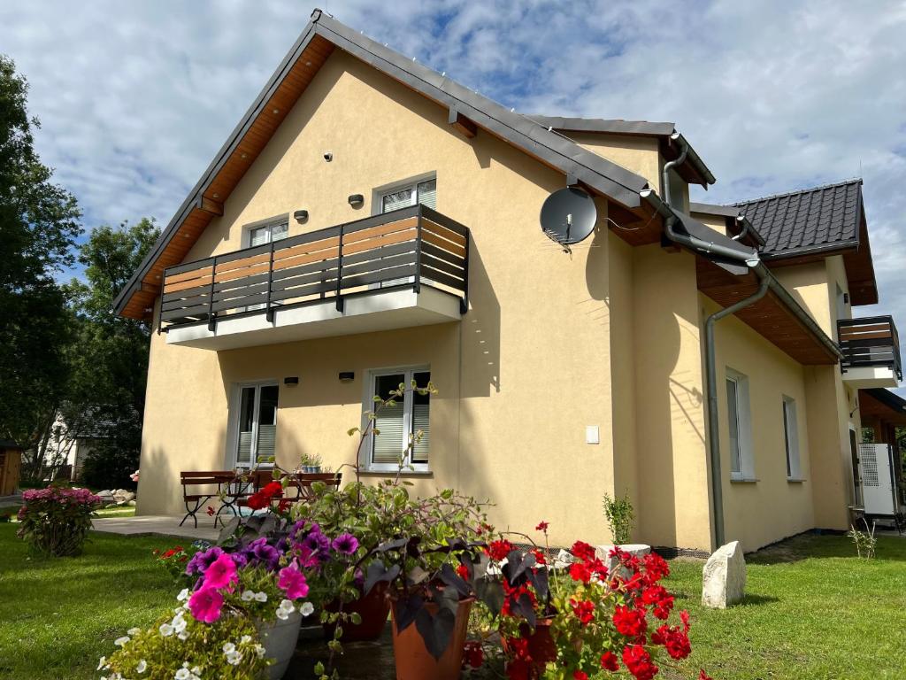 a house with a balcony and flowers in the yard at Zajazd Stronie in Stronie Śląskie