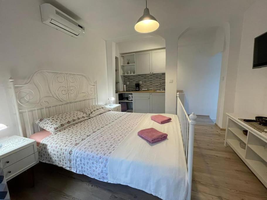 um quarto com uma cama branca e uma cozinha em Studio apartman Barbeta em Grebaštica