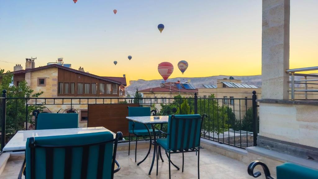 a balcony with a table and chairs and hot air balloons at Rocca Stone House in Goreme