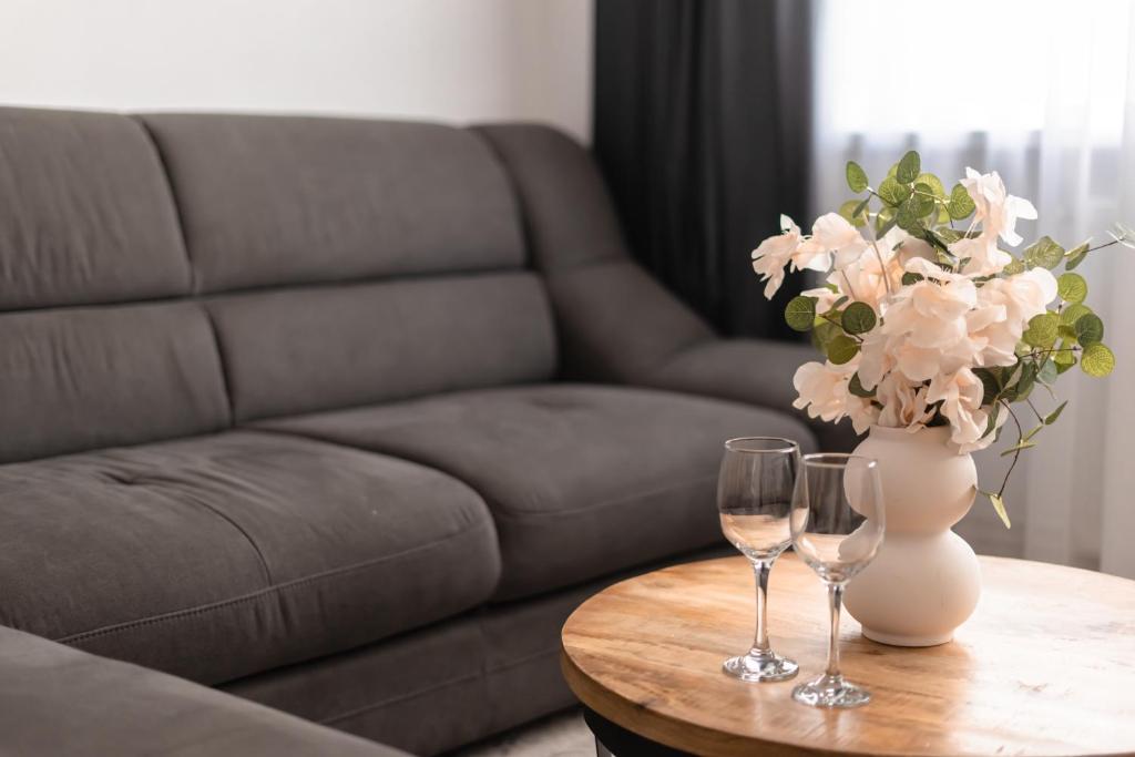 a table with two wine glasses and a vase with flowers at Central Station Two-Bedroom Family Apartment in Timişoara