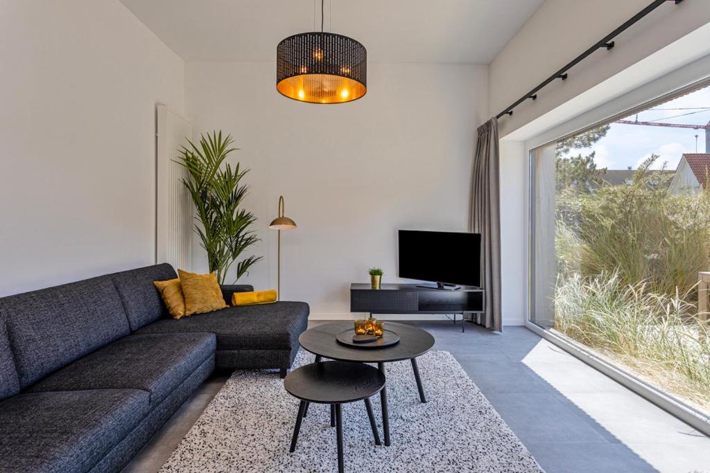 a living room with a couch and a table at Luxe strandappartement met zonneterras & parking in Koksijde