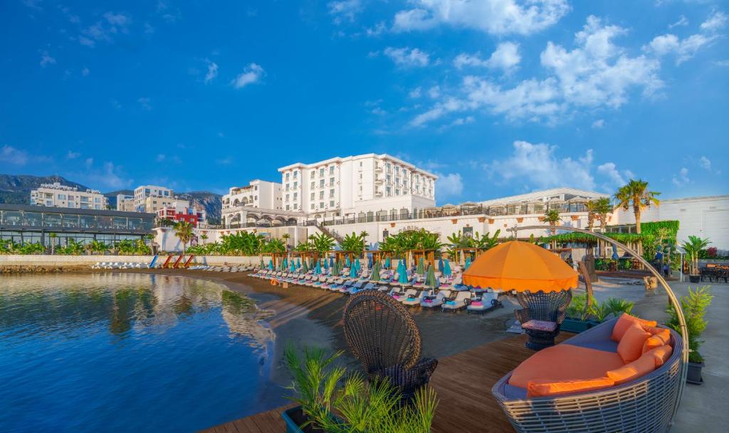 um resort com cadeiras e um guarda-sol ao lado de uma massa de água em Les Ambassadeurs Hotel Casino&Marina em Kyrenia