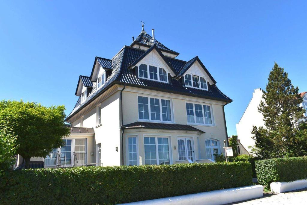 ein großes weißes Haus mit schwarzem Dach in der Unterkunft Villa Seestern Ferienwohnung Nr 04 in Niendorf
