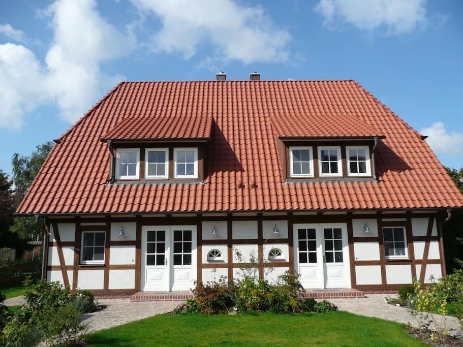 una casa con techo naranja y puertas blancas en Ruhiges Landhaus Krienke - Doppelhaus mit Sauna & Kamin, en Rankwitz