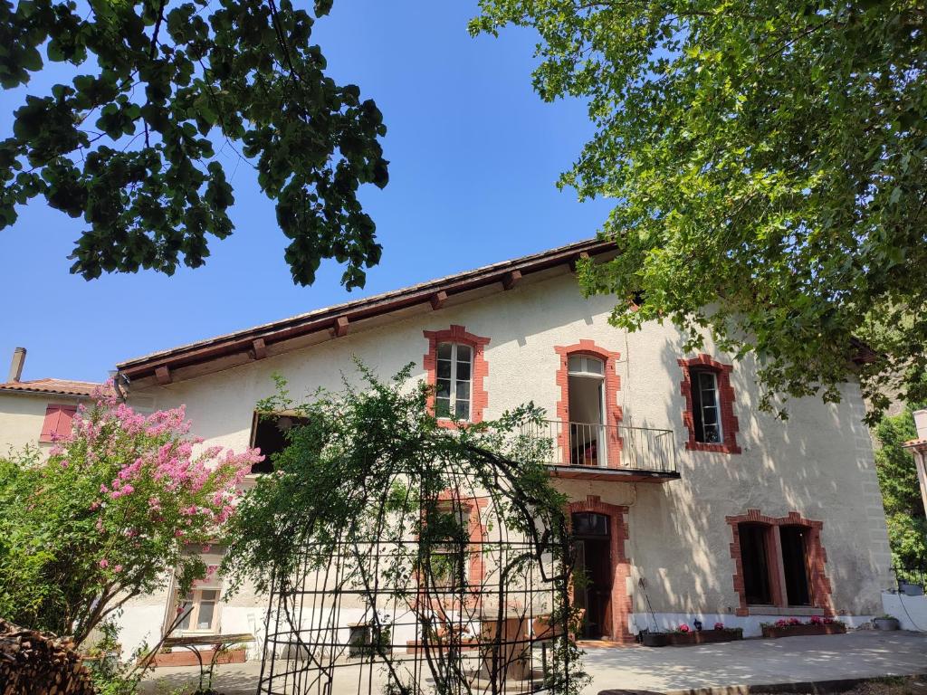 an old white house with red windows at La Scierie in Quillan