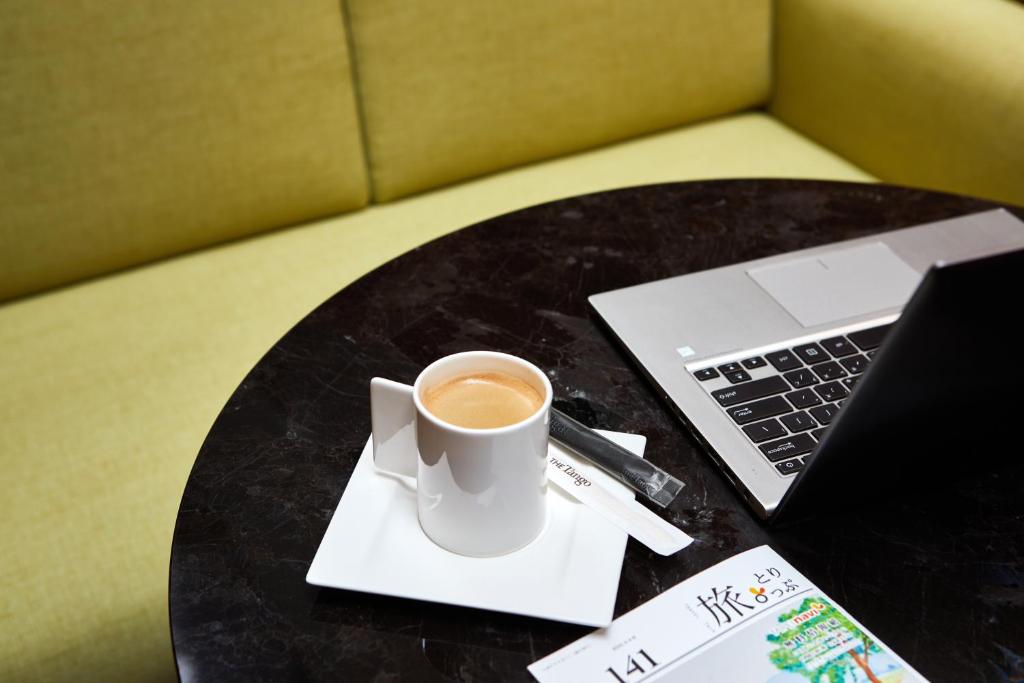 a cup of coffee sitting on a table with a laptop at The Tango Hotel Taipei Nanshi in Taipei