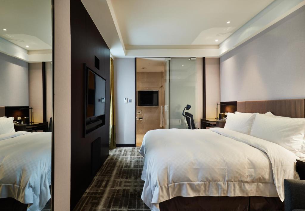 a hotel room with two beds and a mirror at The Tango Hotel Taipei Nanshi in Taipei