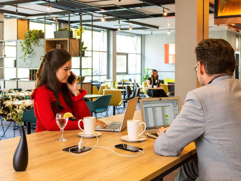 a man and a woman sitting at a table with laptops at ibis Hotel Dortmund City in Dortmund