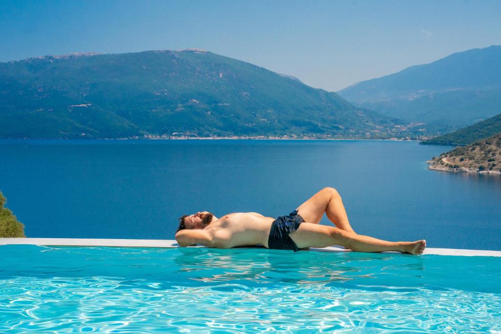 a man laying on the edge of a swimming pool in the water at Villa Fortuna in Ayia Evfimia