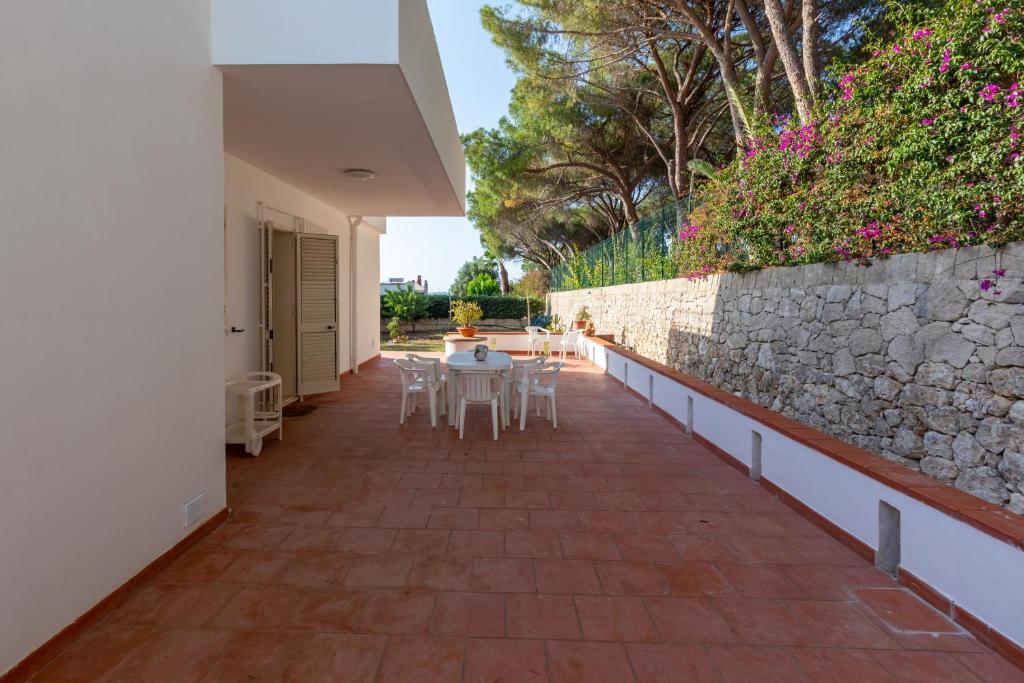a patio with tables and chairs and a stone wall at L'isola di Gianni by Ortigia Apartments in Plemmirio